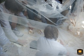 Guastalla, Italy - San Martino Parish: Following the rice toss, young wedding guests gather under the bride's veil, playfully collecting more rice to throw. Dreamlike image.